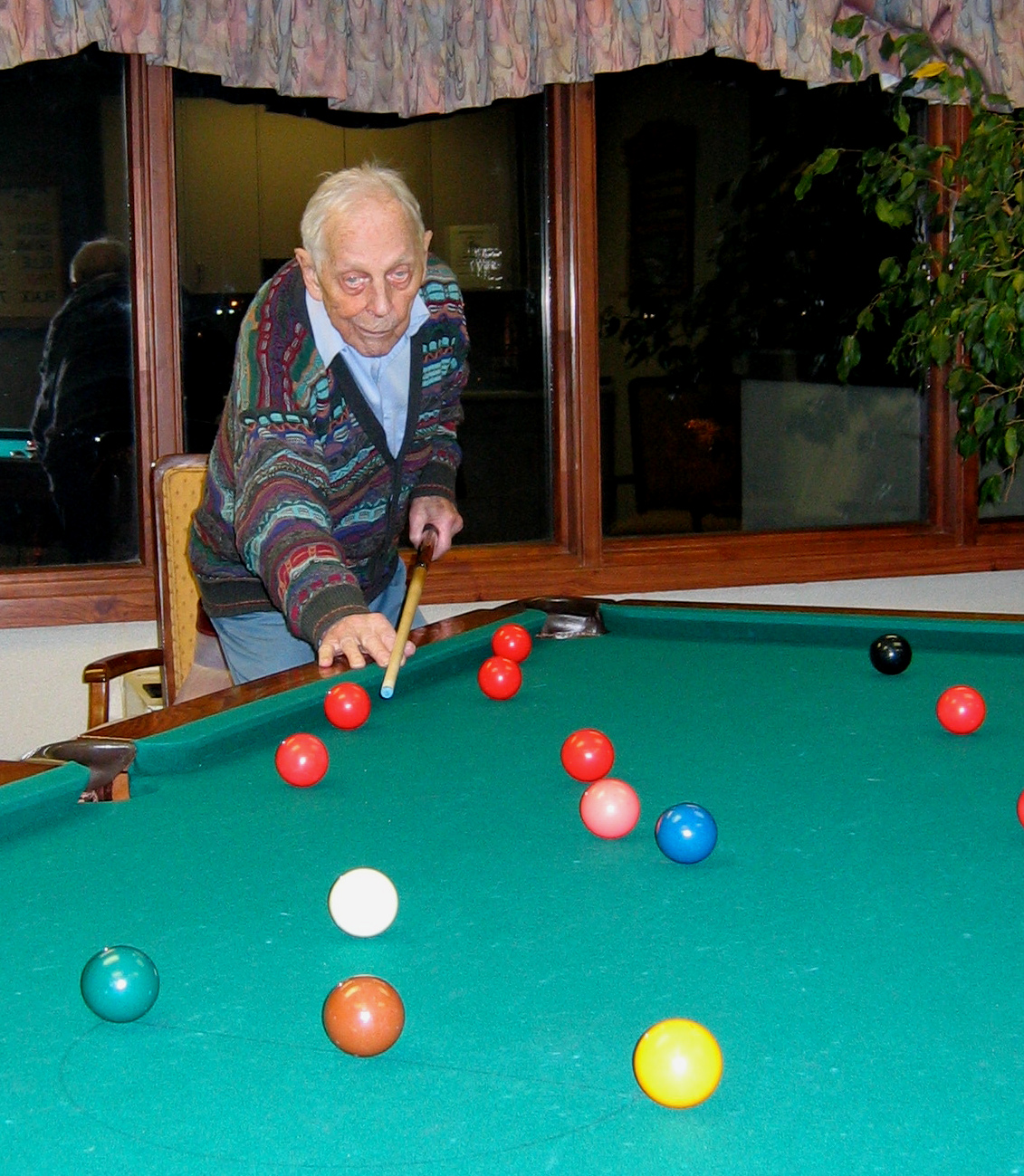 Photo shows Jules Pavio lining up a shot on pool table on his 92nd birthday.
